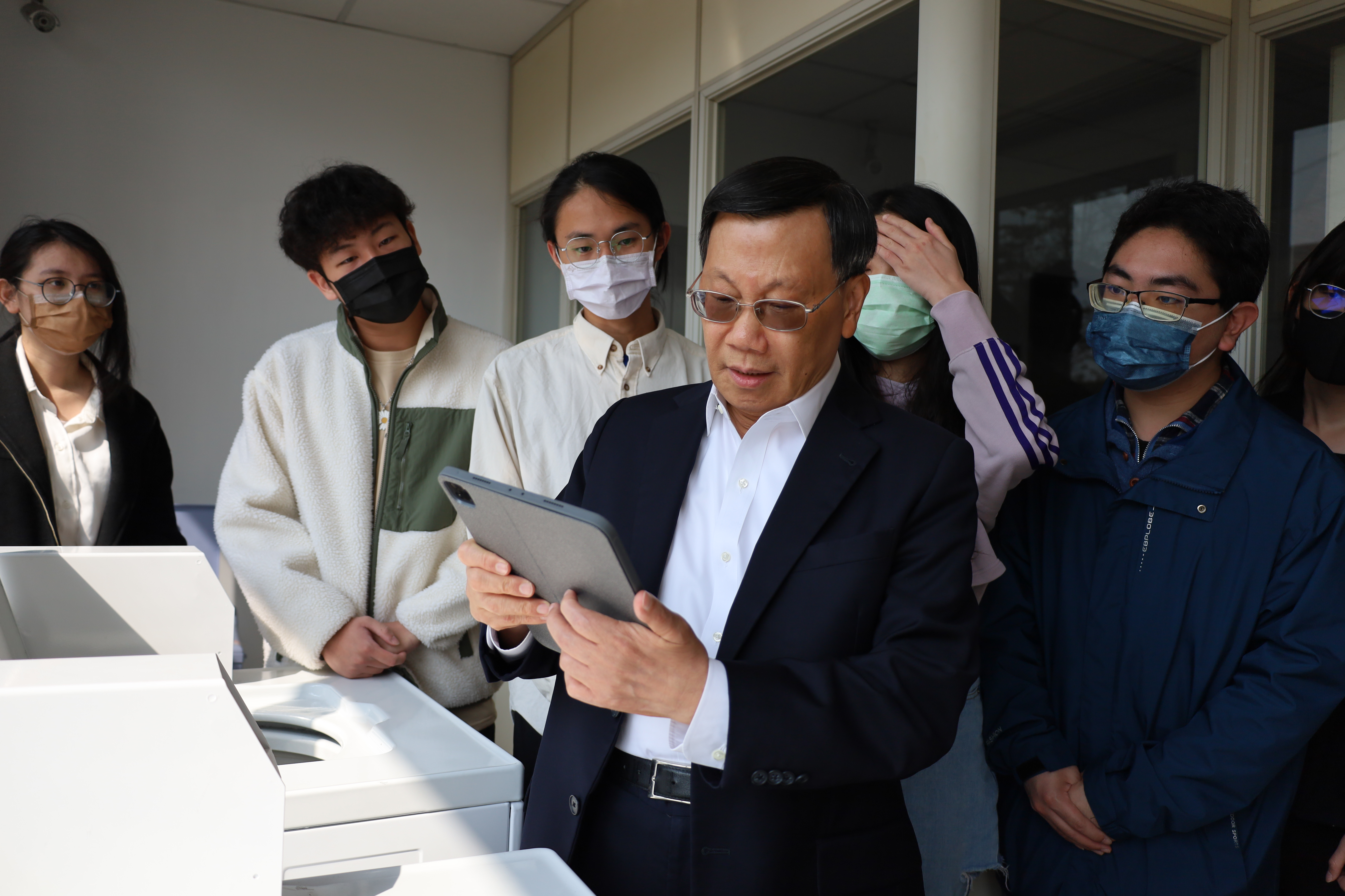 圖為亞大校長蔡進發(中)，試用以APP查看宿舍各樓層i-washing洗衣機使用狀態。